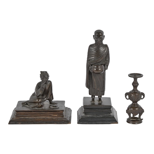 635 - A Burmese bronze figure of a Buddhist monk, collecting arms, on an ebonised base with trade label fo... 