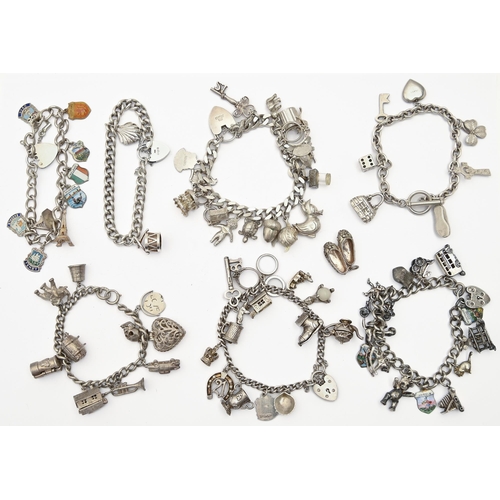 86 - Six silver charm bracelets and another, with enamelled shields, various lengths, 9ozs 10dwts... 