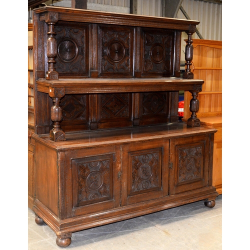 949 - An early Victorian carved oak buffet, the lower part enclosed by three carved panelled doors, on tur... 