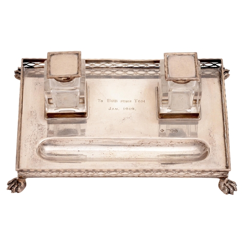 283 - A George V silver inkstand, the rectangular tray with pierced gallery, on paw feet, set with a pair ... 