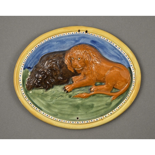 376 - A Pratt Ware plaque, early 19th c, moulded in relief with two reclining lions, 28.5cm diam... 