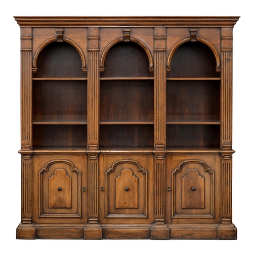 959 - An antique-style walnut bookcase, the upper part with triple arched top sections, flanked by moulded... 