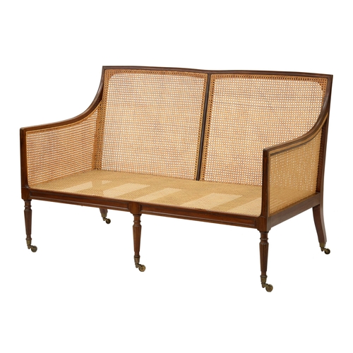 996 - An Edwardian mahogany and caned twin chairback settee, in Regency style,  on six tapering legs and b... 