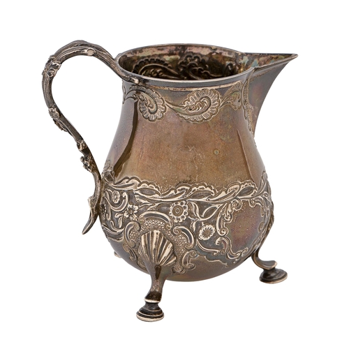 251 - A William IV silver cream jug, with rustic floral handle and crisply chased scrolling foliage on a m... 