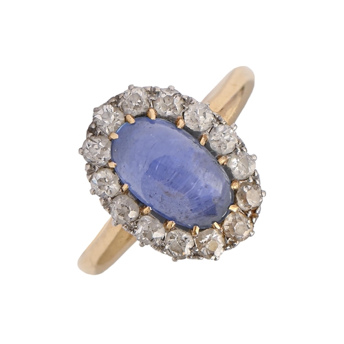 56 - A sapphire and diamond ring, the single sapphire cabochon surrounded by evenly sized old cut diamond... 