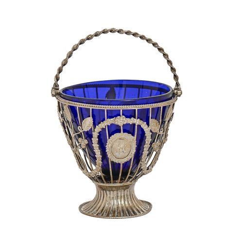 215 - A George III silver wirework sugar basket, applied with leaves and berries, blue glass liner, 16cm h... 