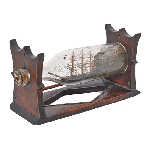 594 - A late Victorian ship in a bottle, on contemporary stained wood stand, 13cm h