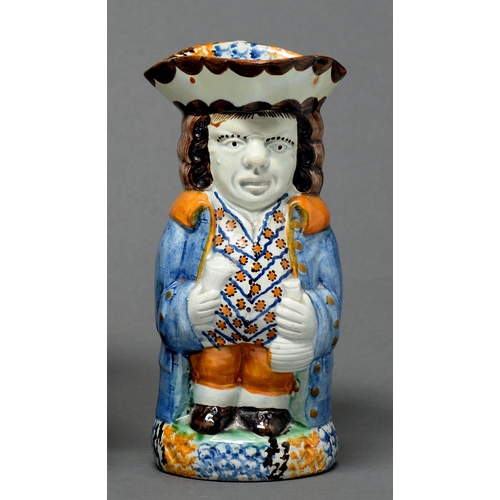 346 - A Prattware toby jug, c1820, modelled standing with figural handle, sponged in a typical blue, green... 