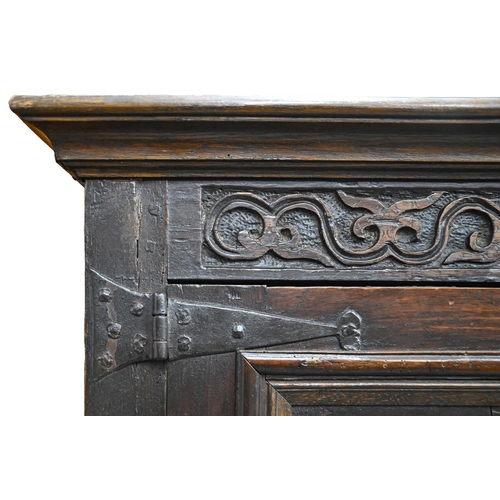 1035 - A Queen Anne oak joined clothes press, dated 1704, with moulded cavetto cornice, the frieze carved w... 