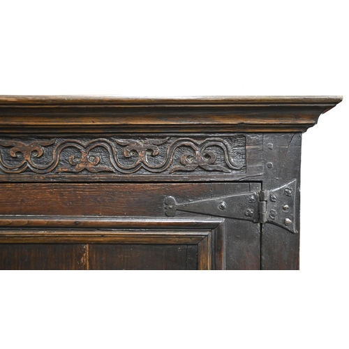 1035 - A Queen Anne oak joined clothes press, dated 1704, with moulded cavetto cornice, the frieze carved w... 