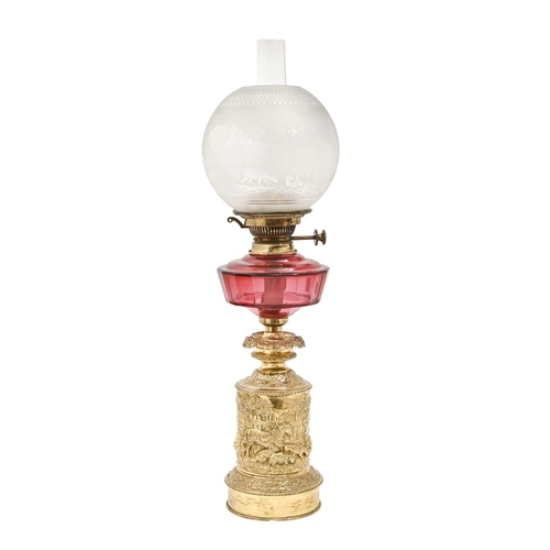 466 - A French cranberry glass oil lamp, c1880, the brass base decorated in relief with a farmyard scene, ... 