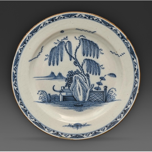 547 - An English Delftware dish, Lambeth, c1760, painted in cobalt with willow tree, rock and fence, 34.5c... 