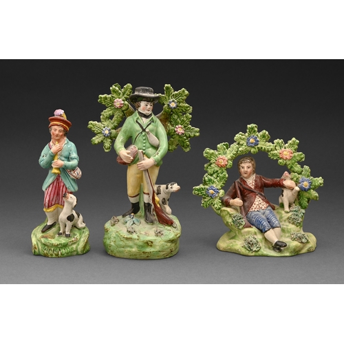 296 - A John Walton pearlware figure of huntsman, c1820, with a dog and before bocage, painted in overglaz... 