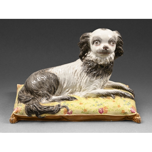 288 - A Continental porcelain model of a spaniel, late 19th c, lying on a floral cushion with gilt tassels... 