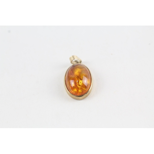 100 - 2 x 9ct gold topaz & processed amber pendants (3.9g)