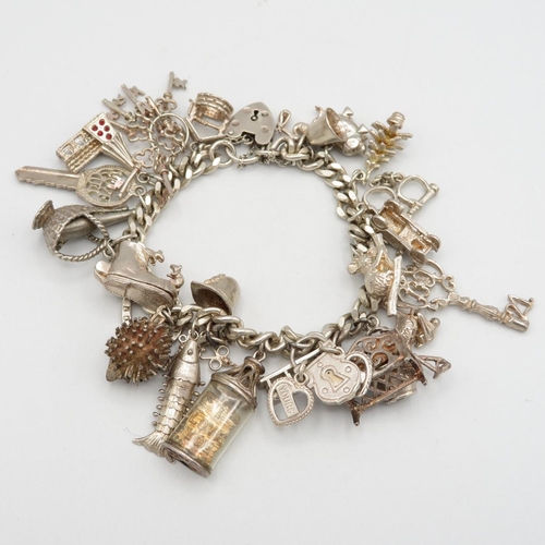 Silver charm bracelet with assortment of charms, some articulated.   75.1g