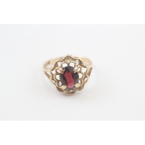 106 - 10kt gold floral surround garnet set dress ring (2.2g) Size  I