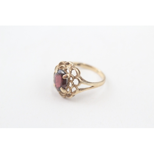 106 - 10kt gold floral surround garnet set dress ring (2.2g) Size  I