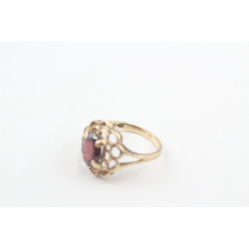 106 - 10kt gold floral surround garnet set dress ring (2.2g) Size  I