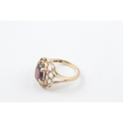 106 - 10kt gold floral surround garnet set dress ring (2.2g) Size  I