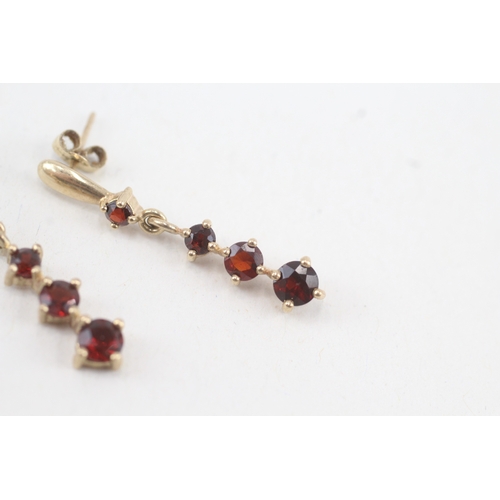 117 - 9ct gold graduated garnet drop earrings with scroll backs (1.9g)