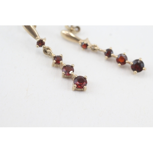 117 - 9ct gold graduated garnet drop earrings with scroll backs (1.9g)