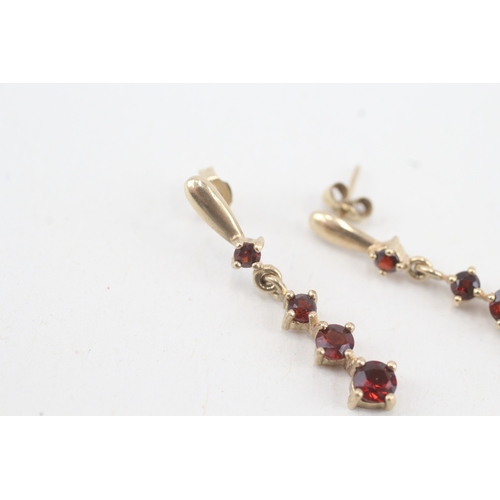 117 - 9ct gold graduated garnet drop earrings with scroll backs (1.9g)