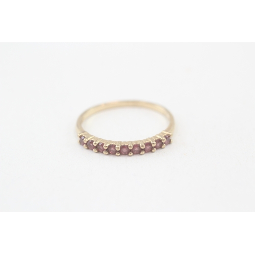 113 - 9ct gold garnet half eternity ring, claw set (1.3g) AS SEEN - MISHAPEN Size  P