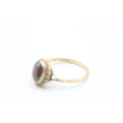 174 - 9ct gold rope edged oval cut garnet dress ring (2.2g) Size  Q