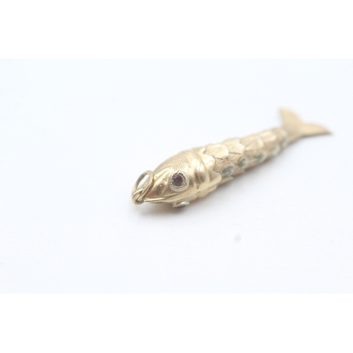 101 - 9ct gold articulated fish pendant with garnet eyes (1.5g)