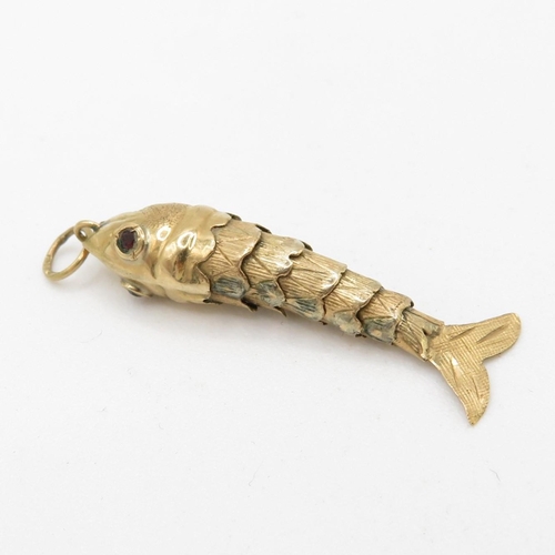 101 - 9ct gold articulated fish pendant with garnet eyes (1.5g)