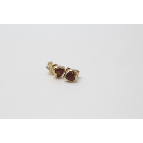 91 - 2 x 9ct gold heart cut amethyst and garnet set stud earrings (1.2g)