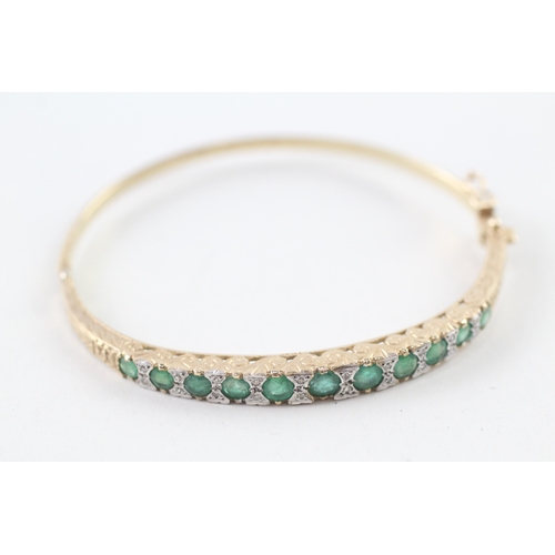 97 - 9ct gold diamond and emerald set bangle (11.6g)