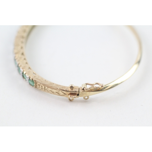 97 - 9ct gold diamond and emerald set bangle (11.6g)