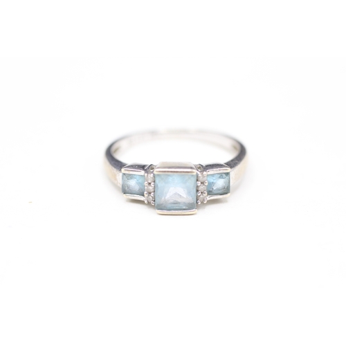 110 - 9ct white gold topaz three stone ring with diamond spacers (2.3g) Size M