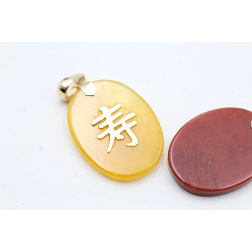 210 - 2x 9ct gold red & yellow gemstone pendants with Chinese symbols (4.3g)