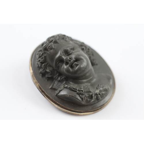 131 - Low carat gold rimmed large lavastone cameo cherub brooch (26.5g)