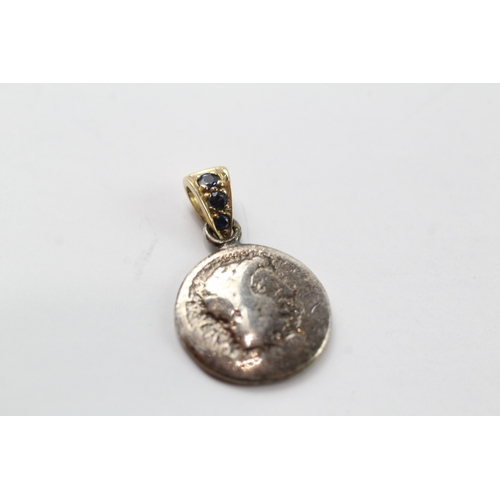 456 - A silver coin mounted with a 9ct gold and sapphire set bail (1.9g)