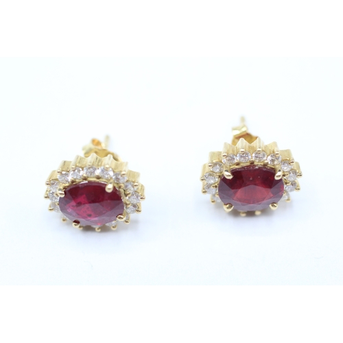 229 - 18ct gold diamond & glass filled ruby oval cluster stud earrings (5.6g)