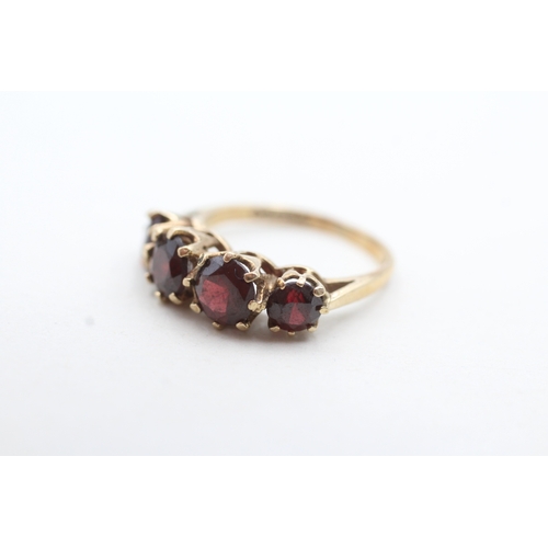 66 - 9ct gold four round cut red gemstone ring (3g) Size M