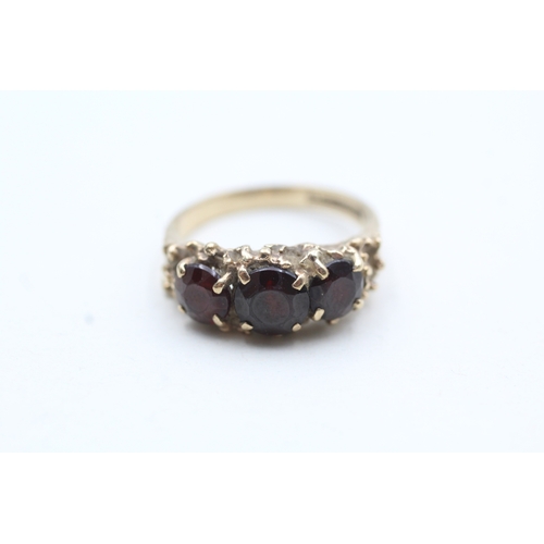 101 - 9ct gold garnet three stone ring (3.6g) Size N