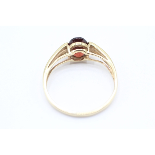 173 - 9ct gold oval cut garnet dress ring with split shoulders (2g)