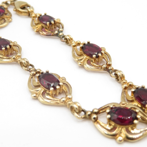 287 - 9ct gold garnet set spider link bracelet (11g)