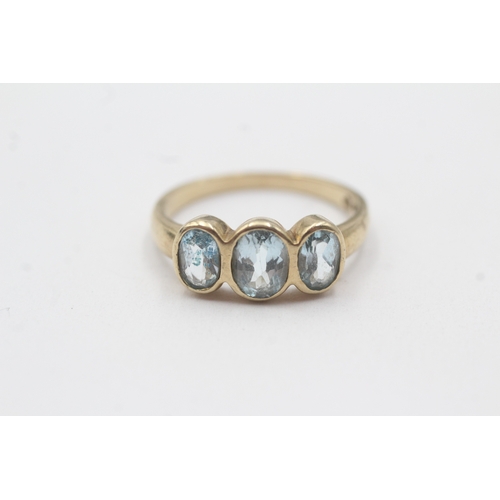 135 - 9ct gold bezel set blue topaz trilogy ring (2.9g) Size P