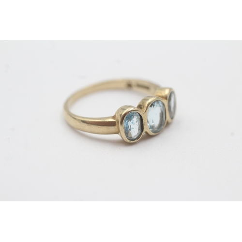 135 - 9ct gold bezel set blue topaz trilogy ring (2.9g) Size P