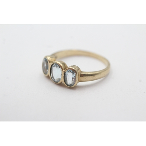 135 - 9ct gold bezel set blue topaz trilogy ring (2.9g) Size P