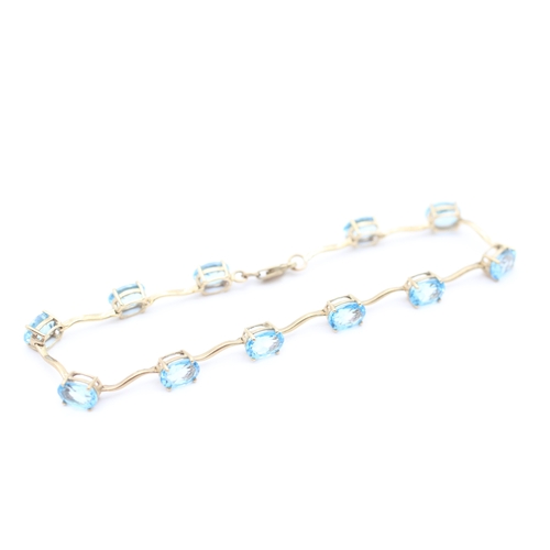 4 - 9ct gold blue topaz set station bracelet (6g)
