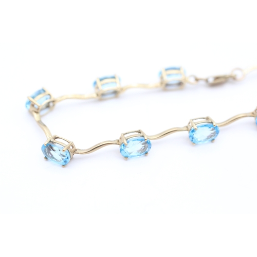 4 - 9ct gold blue topaz set station bracelet (6g)