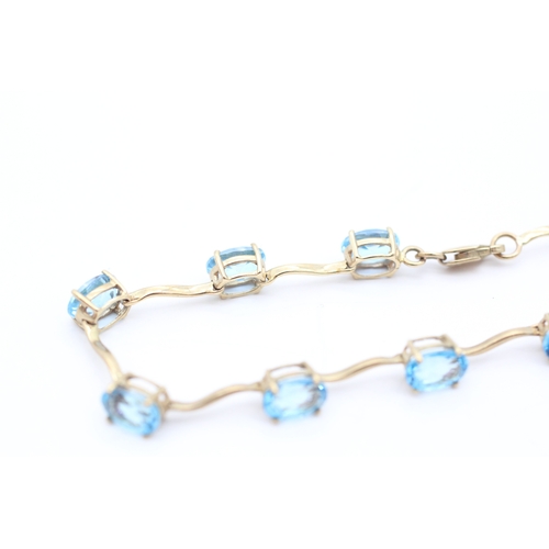 4 - 9ct gold blue topaz set station bracelet (6g)