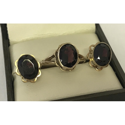 12 - A 9ct gold garnet set dress ring and matching stud style earrings. Oval cut garnets set in scallop e... 